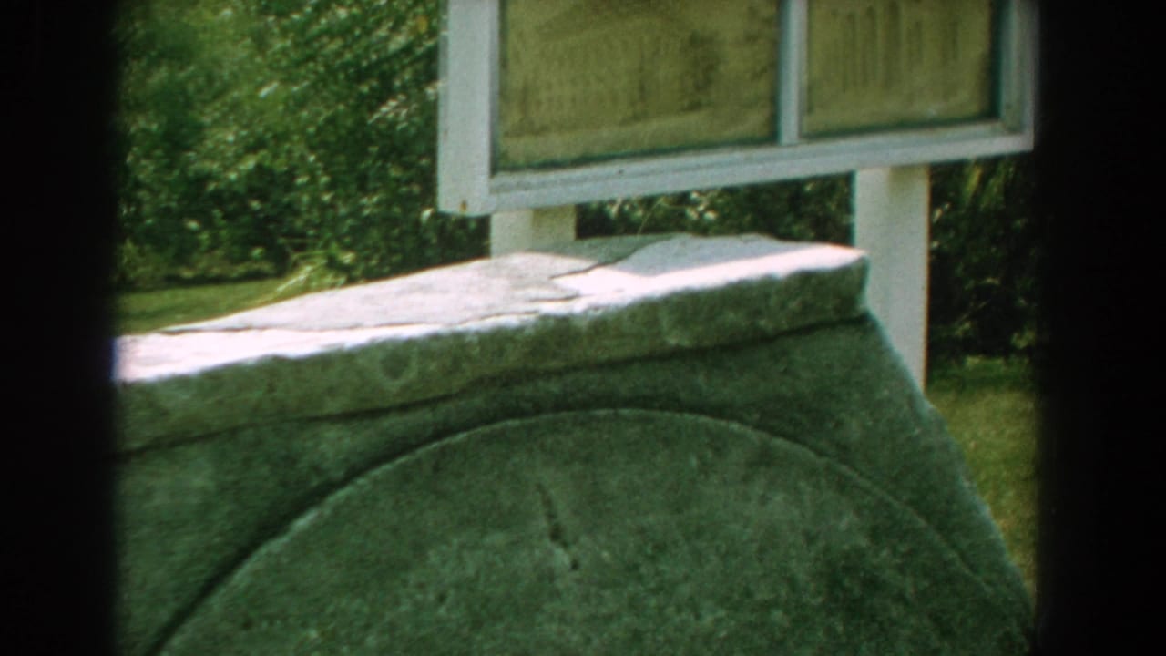 Stone monument below a partially visible white-framed outdoor sign.