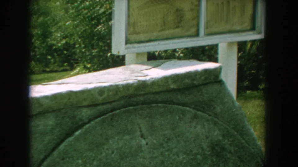 Florida 1959 8mm frame with the stone marker in front and the lower part of a white-framed interpretive sign behind it.