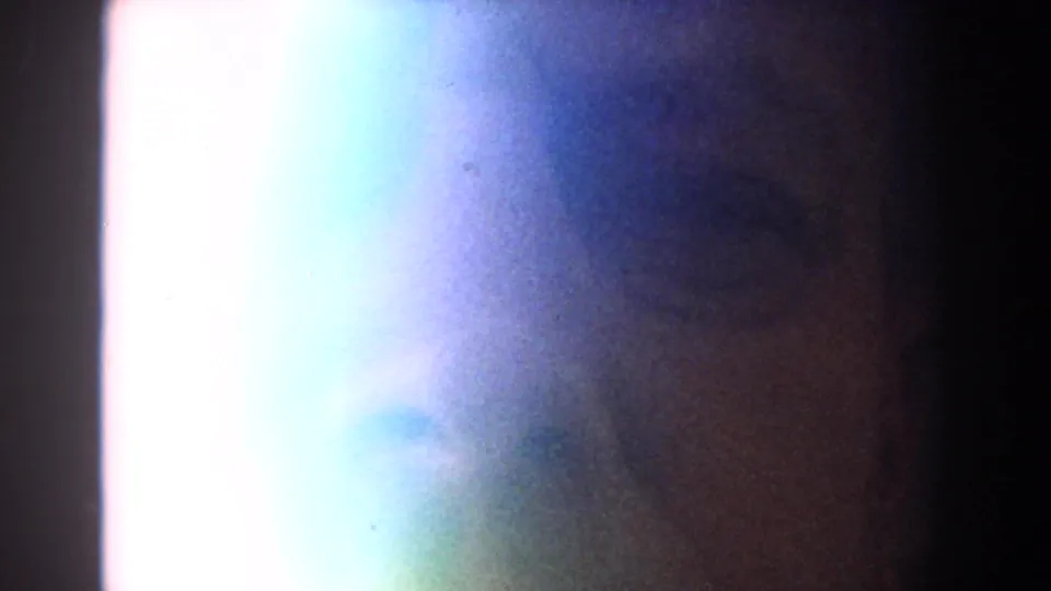 Final 8mm frame shifts into bright flare and soft color wash, with only indistinct shapes visible.