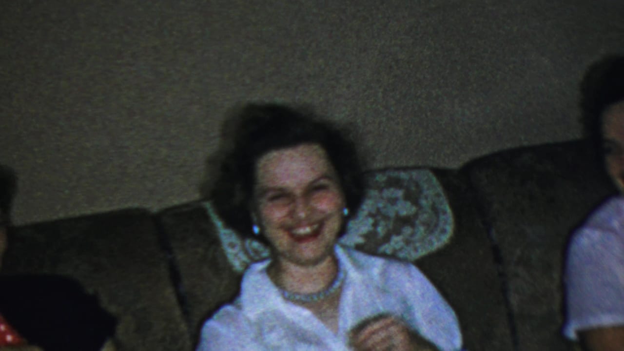 In the 1959 Paramus living-room footage, a woman smiles broadly on the sofa with another seated figure partly visible nearby.