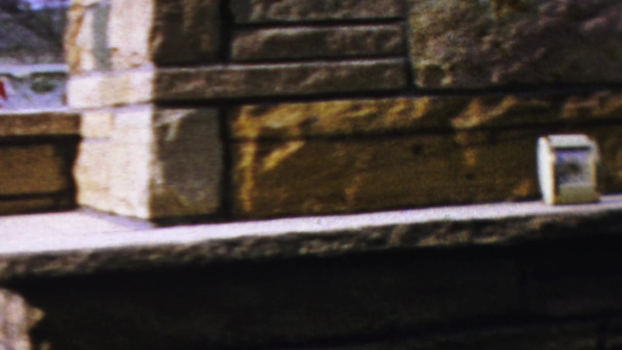 A handheld 8mm frame shows the stone hearth, pale ledge, and small rectangular object near the right side.