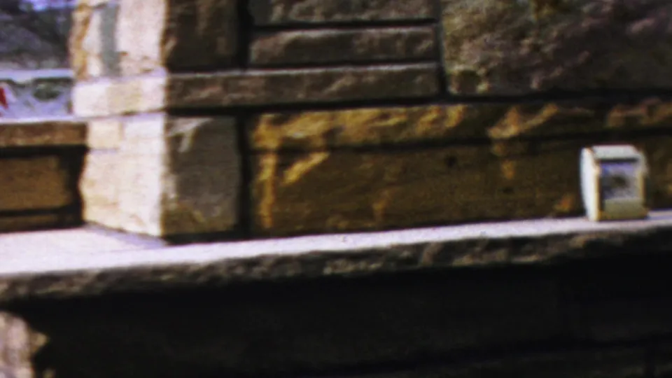 A handheld 8mm frame shows the stone hearth, pale ledge, and small rectangular object near the right side.