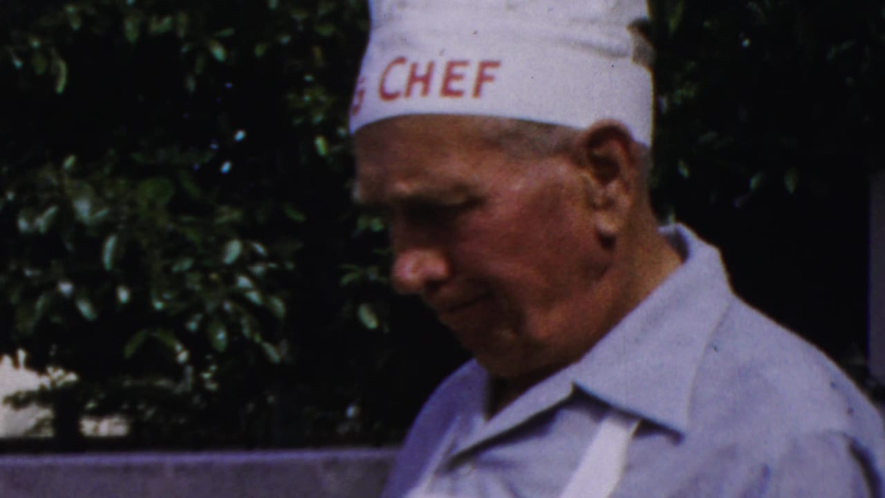 Close 1959 Paramus frame of the chef-hatted man in profile, with red CHEF lettering visible on the hat and greenery behind him.