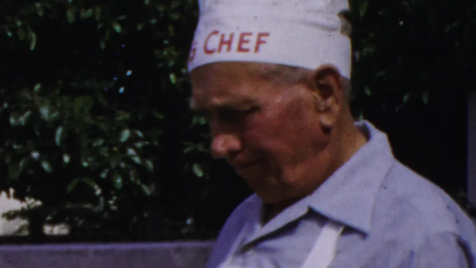 Close 1959 Paramus frame of the chef-hatted man in profile, with red CHEF lettering visible on the hat and greenery behind him.