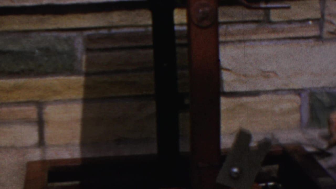 The home-movie frame shows the lower grill structure, stone wall, and part of the cooking area in a backyard setting.