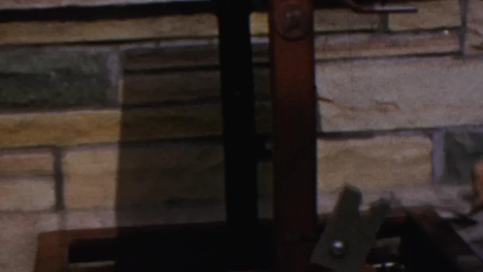 The home-movie frame shows the lower grill structure, stone wall, and part of the cooking area in a backyard setting.