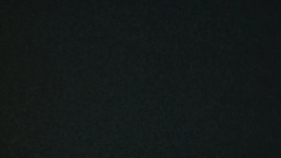 The 1959 Paramus home-movie frame is underexposed, with only faint shaded forms from the outdoor setting visible.