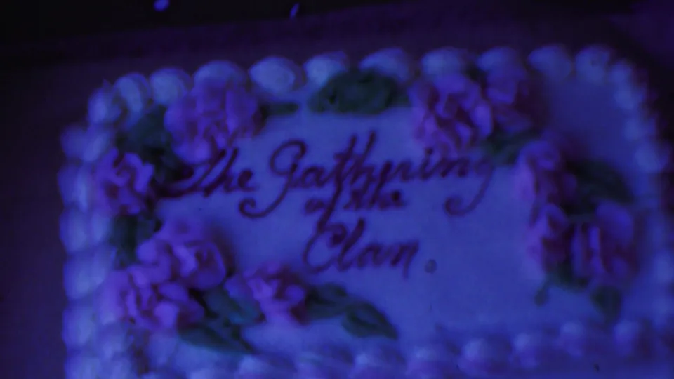 Final still from the 1959 Paramus clip showing the decorated cake under blue-purple shifted 8mm color.
