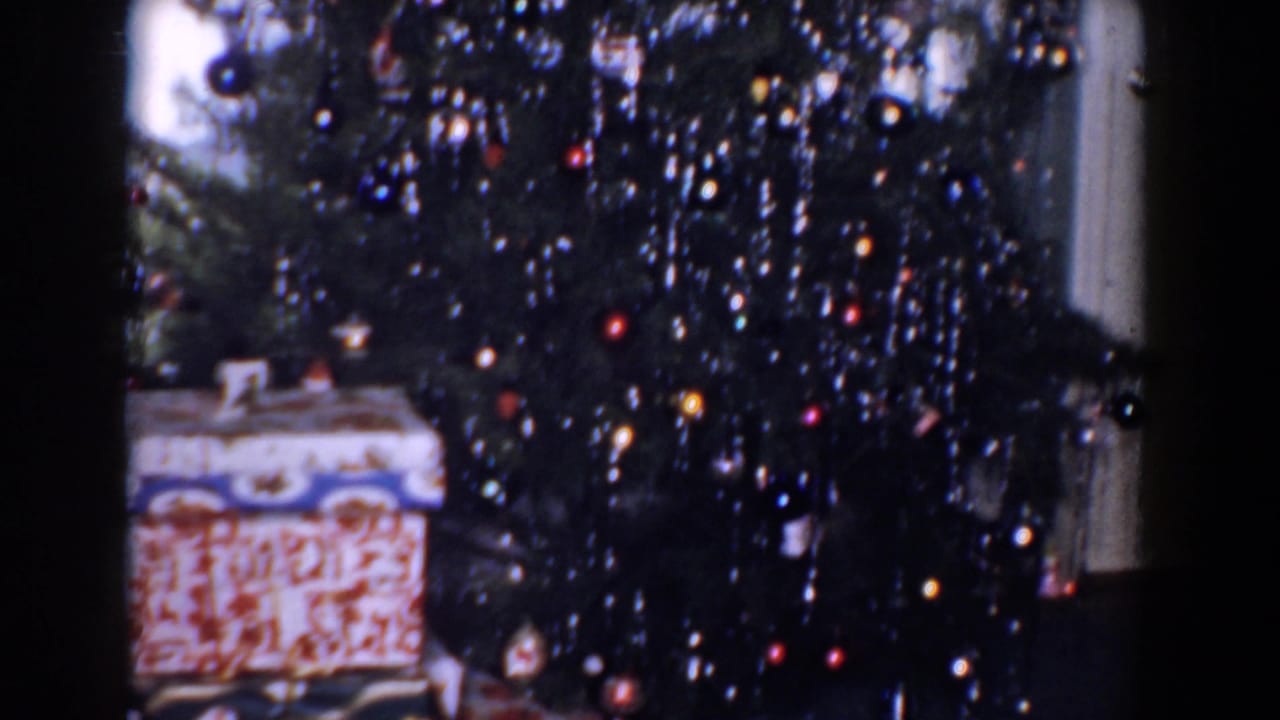 Decorated Christmas tree with tinsel, ornaments, and wrapped gifts at the base.