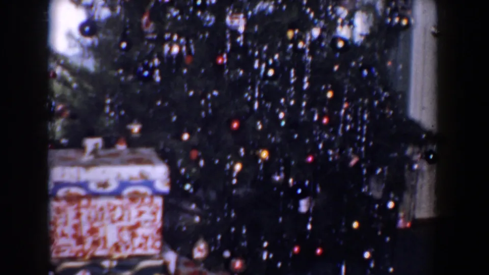 1960 Bel Air, Maryland home-movie view of a decorated Christmas tree with tinsel, ornaments, and wrapped presents near the lower branches.