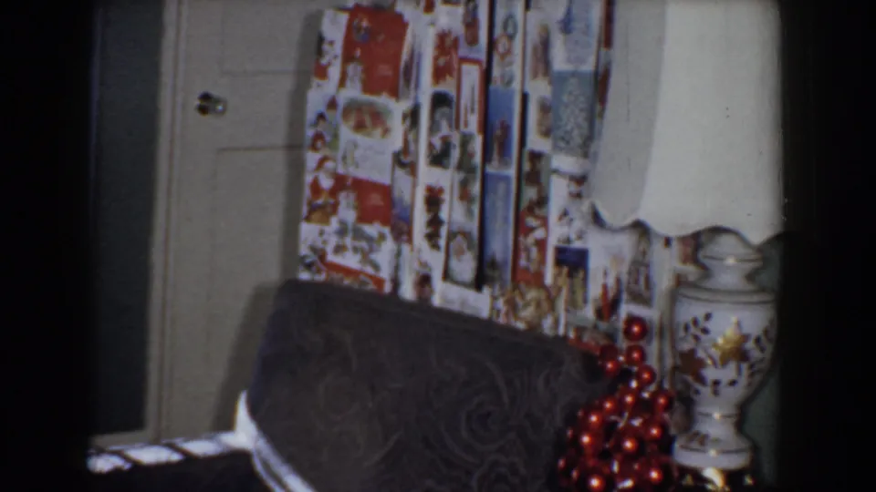 1960 Bel Air, Maryland frame showing wrapped Christmas gifts above a dark chair, with a white door and table lamp visible in the room.