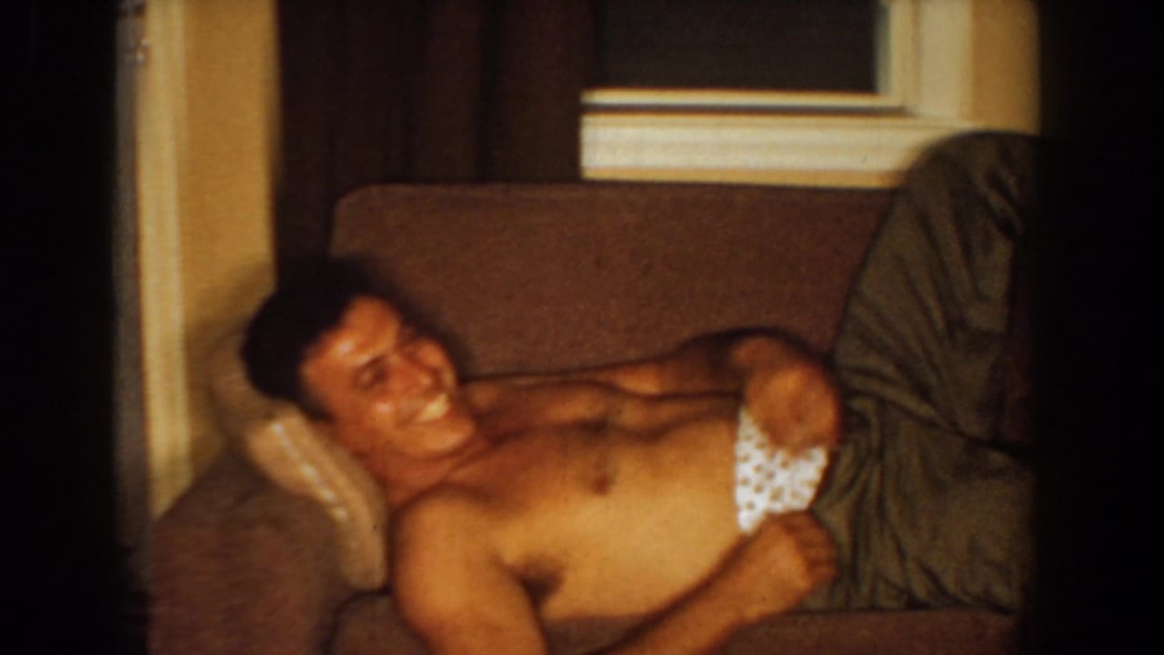 Man laughing on a couch while holding patterned underwear.