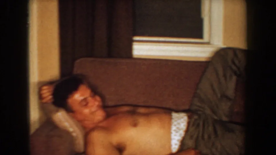 The shirtless man reclines across the couch with patterned underwear visible in a private Bel Air, Maryland living room.