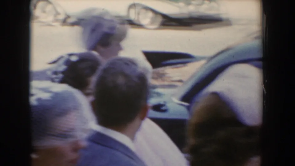 In Bel Air, Maryland in 1960, guests in formal attire crowd around a car as the bride approaches or exits nearby.