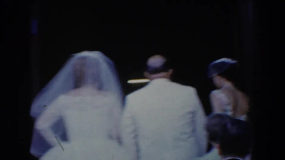 Bel Air, Maryland 1960 frame showing a veiled bride escorted by a man in a light suit toward a building entrance.