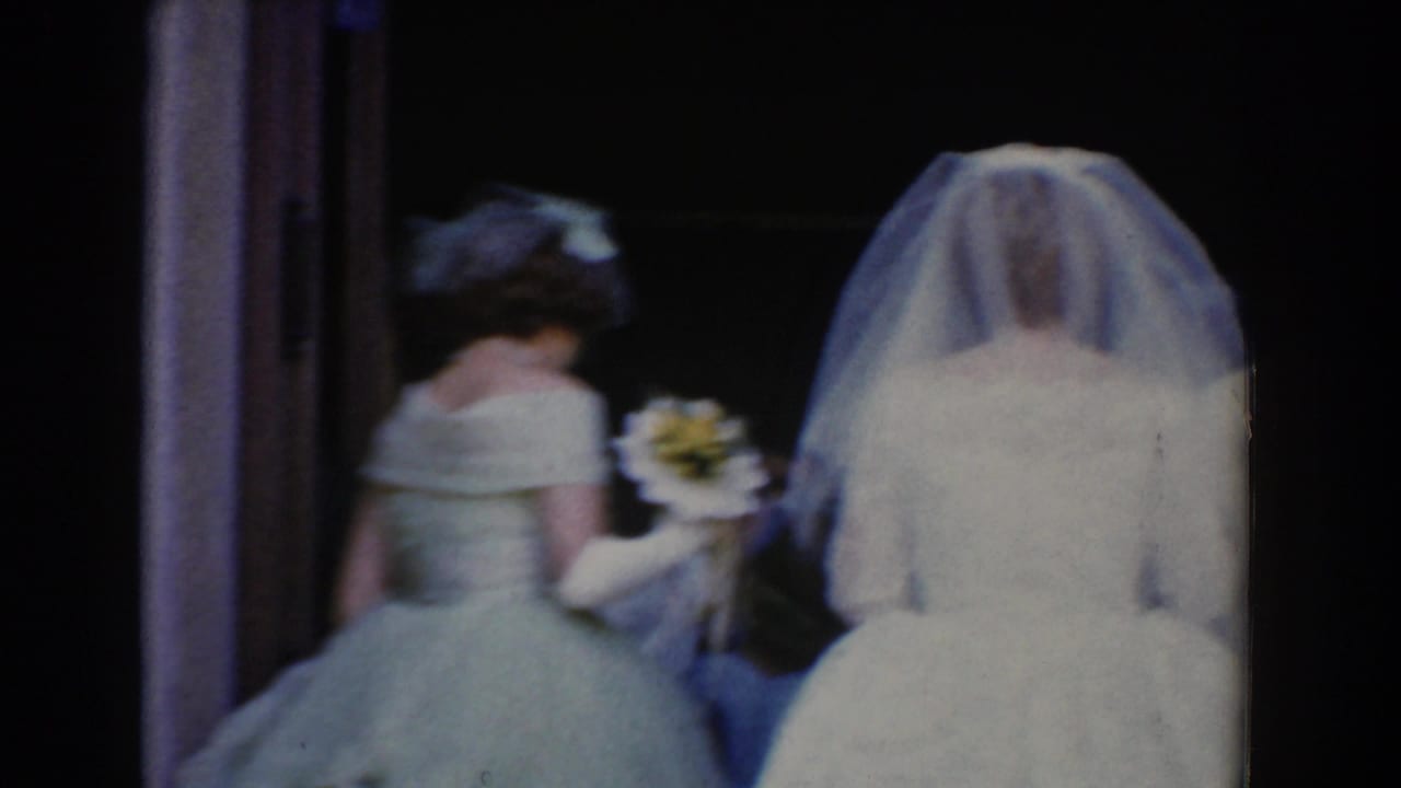 Bride and bridesmaid seen from behind entering a dark church doorway.