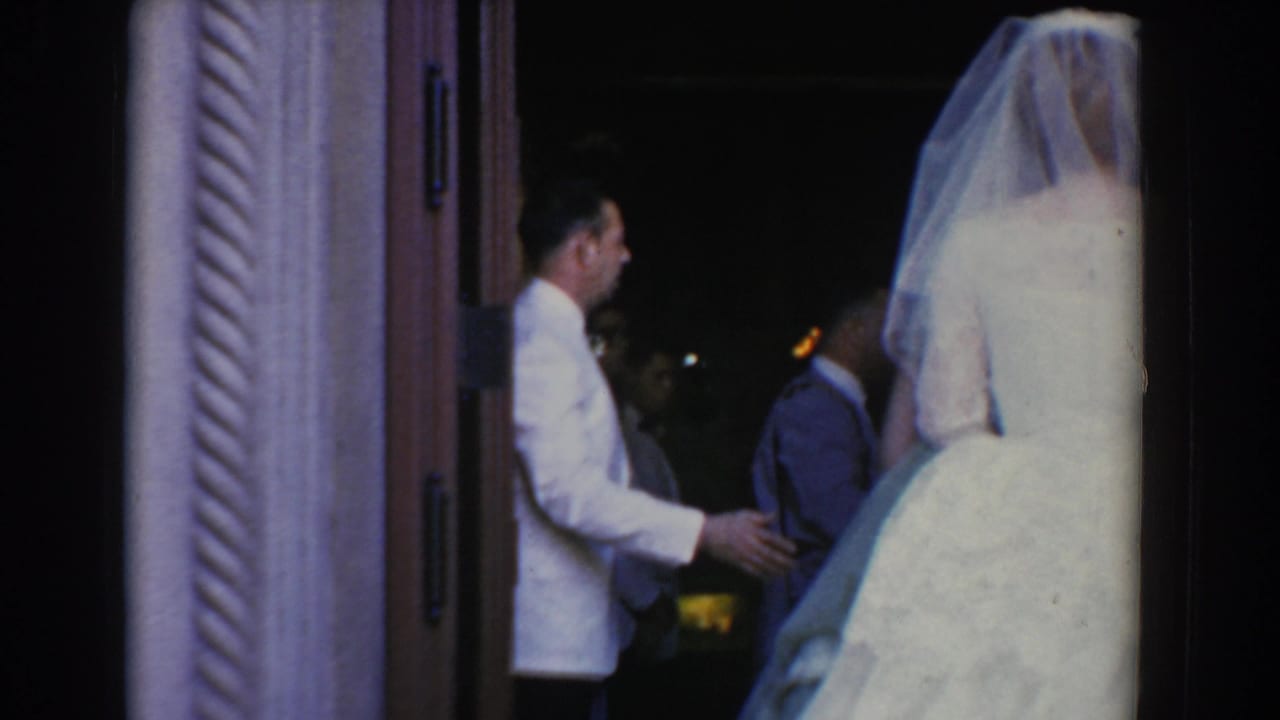 The bride waits at the church doorway in Bel Air, Maryland, with formally dressed men visible in the dim interior.
