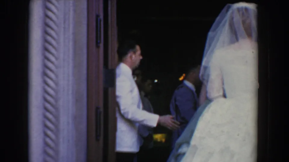 The bride waits at the church doorway in Bel Air, Maryland, with formally dressed men visible in the dim interior.