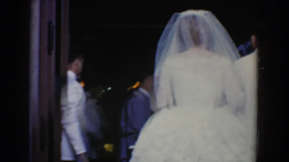 A rear view shows the veiled bride entering the church doorway, with formal guests or attendants partly visible inside.
