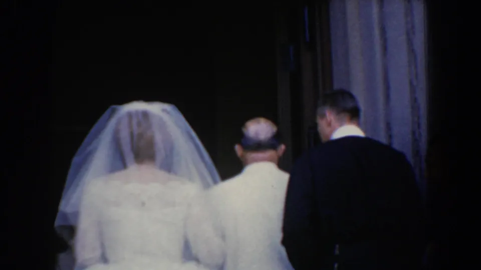 The bride appears to enter the church with her father or escort, followed or accompanied by another formally dressed man.