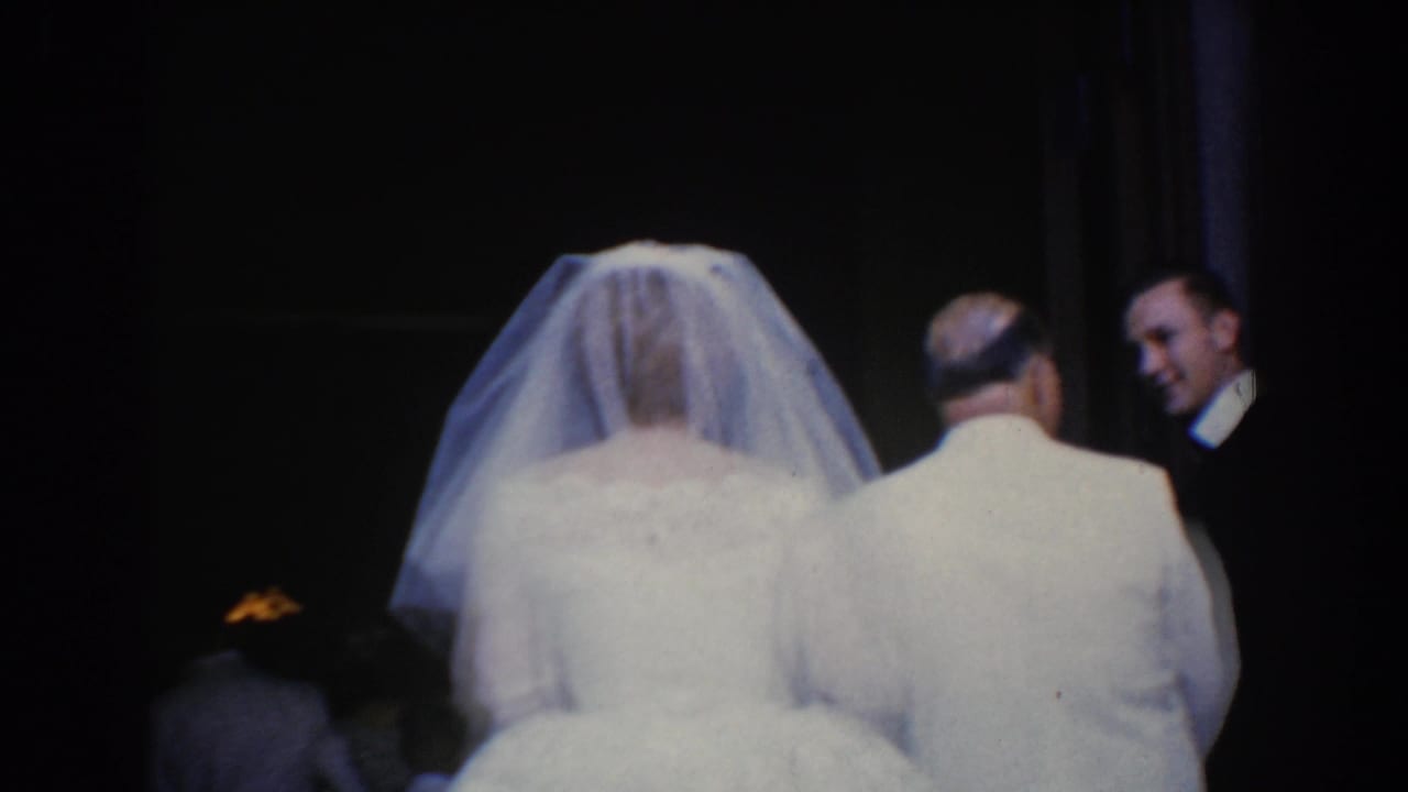 Bride and older man face a dark doorway with two suited men nearby.