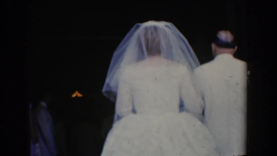 The bride and a man in a light suit are seen from behind near a dark church entrance in the Bel Air, Maryland wedding footage.