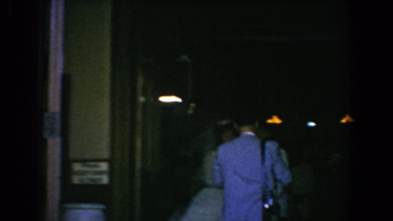 Two suited figures seen from behind near a dark glass doorway.