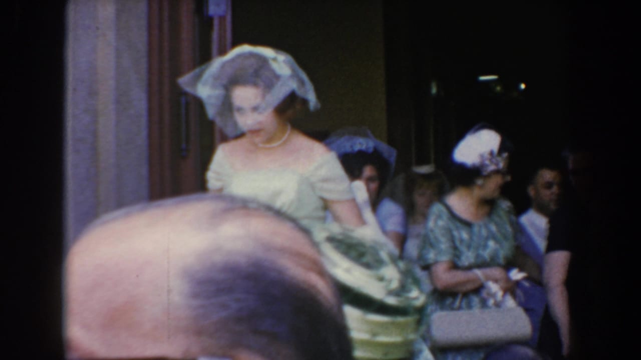 Bride and guests outside a church doorway with a crowd partly blocking the foreground.