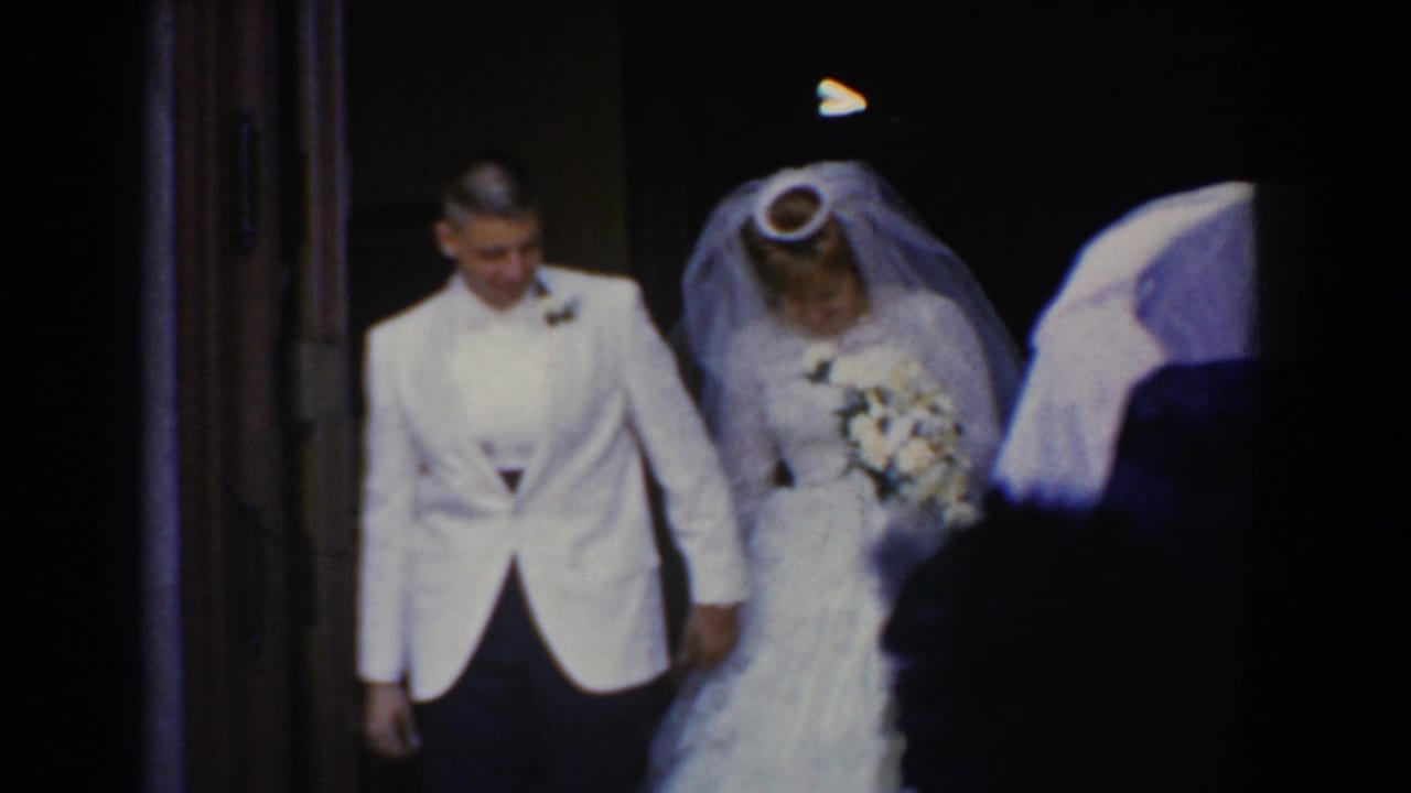 Bride and groom step out through a dark church doorway during a wedding exit.