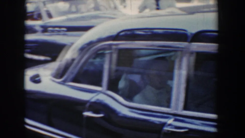 1960 Bel Air, Maryland 8mm frame showing a dark vintage station wagon with passengers visible through side windows.
