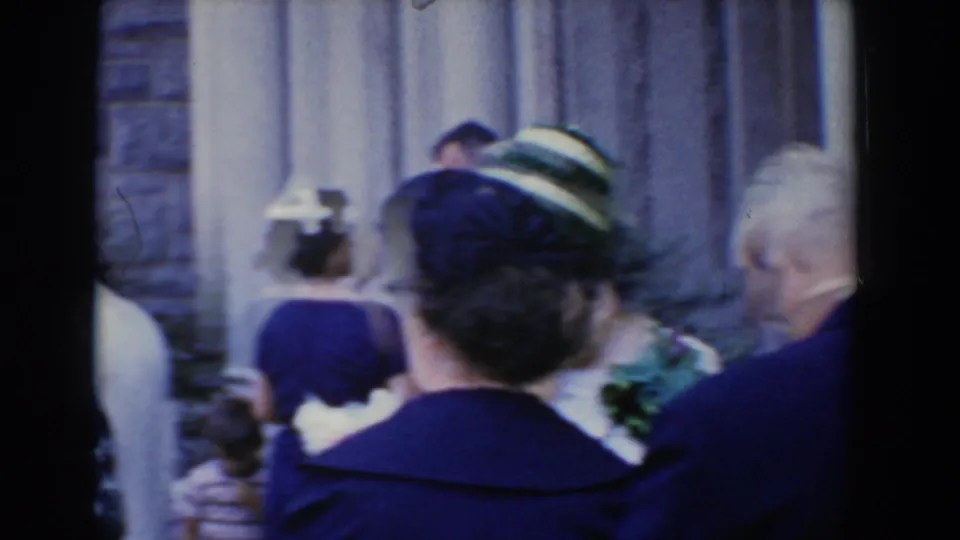 Handheld 1960 Bel Air footage shows formal guests from behind as they cluster near a stone exterior and columned entrance.