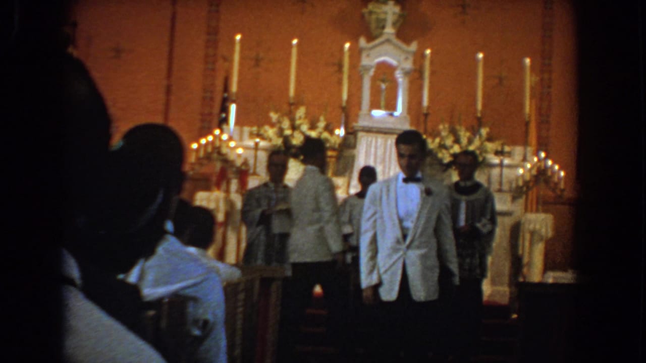 Man in a white jacket walks away from the altar while clergy stand behind him.