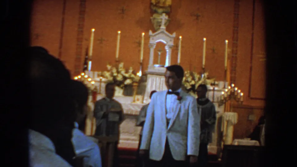 Bel Air, Maryland 1960 home-movie frame of a young man in formal dress before a candlelit altar and clergy.