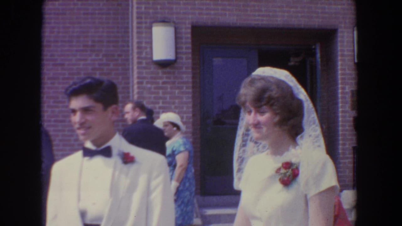 Bride and groom standing outside a brick church with wedding guests behind them.