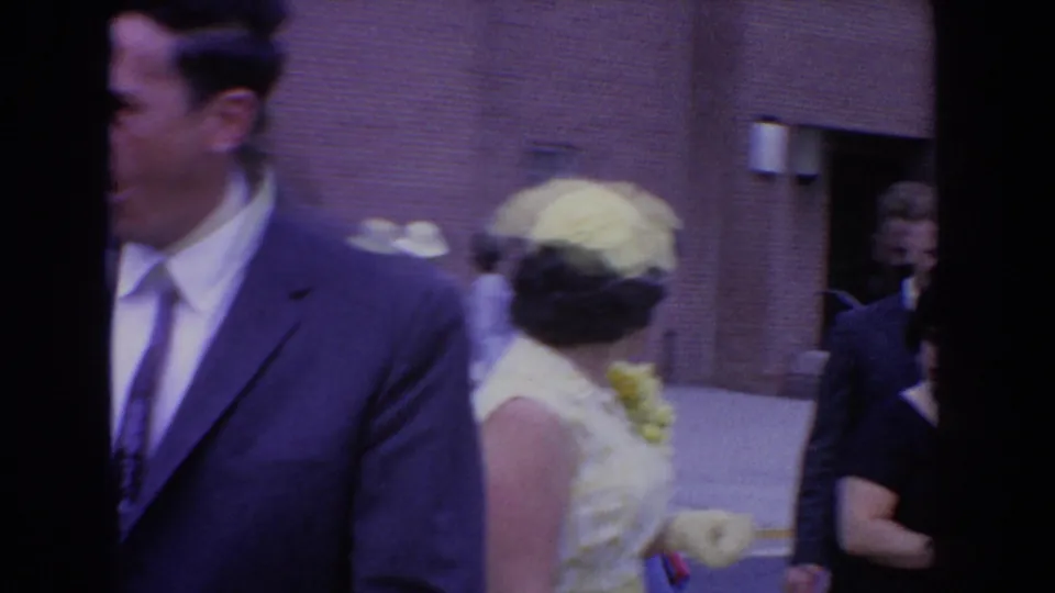 A suited man turns beside a woman in a light dress and hat during the Bel Air, Maryland gathering in 1960.