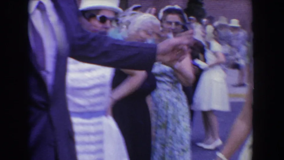 A man in a dark suit gestures while women in dresses, hats, and gloves stand in the Bel Air, Maryland crowd.