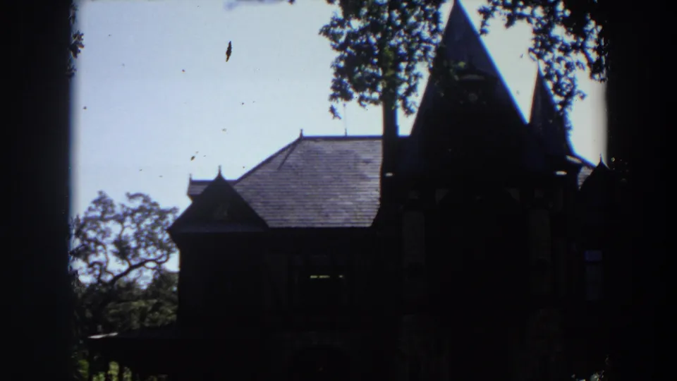 Late frame from the 1964 California clip showing the house mostly in silhouette with rooflines and tree canopy visible.