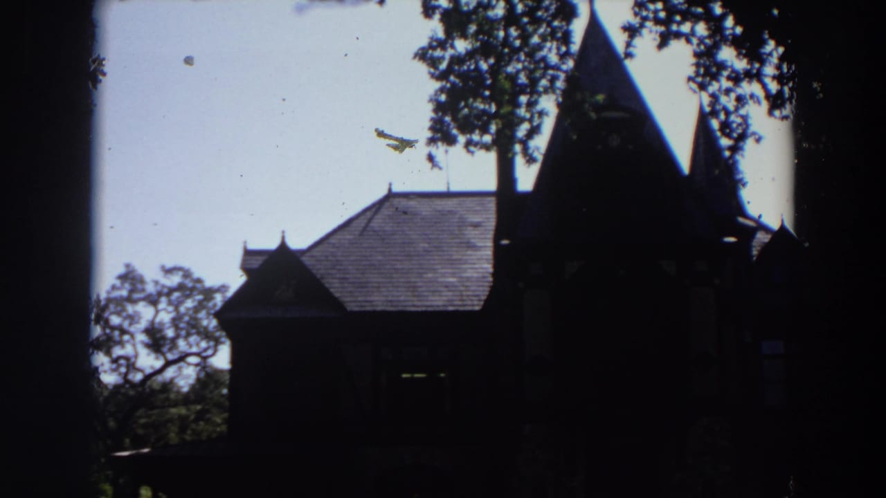 1964 California 8mm frame showing a silhouetted old chapel-like exterior with spires, trees, and bright sky.