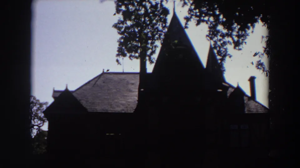 Final 1964 California frame showing the silhouetted chapel-like building, pointed spires, chimney, and overhanging trees.