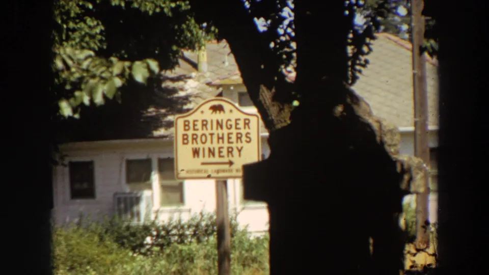 1964 California 8mm frame with a Beringer Brothers Winery sign, bear emblem, trees, and a light-colored building behind it.
