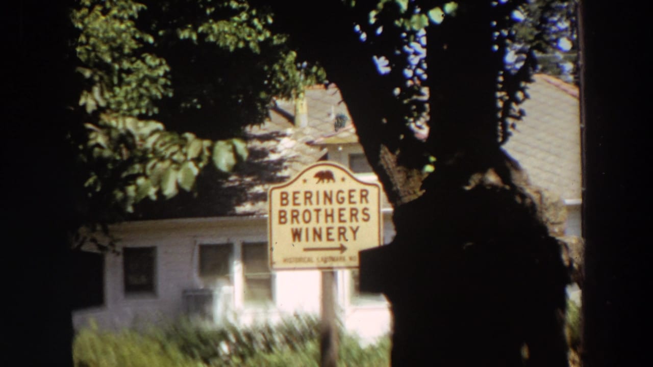 1964 California 8mm frame with a Beringer Brothers Winery sign partially obscured by shaded tree trunks and foliage.