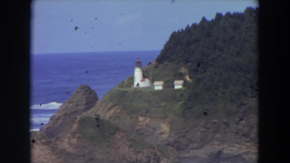 The final frame shows the lighthouse and small outbuildings on the coastal headland, bordered by forest and open Pacific water.