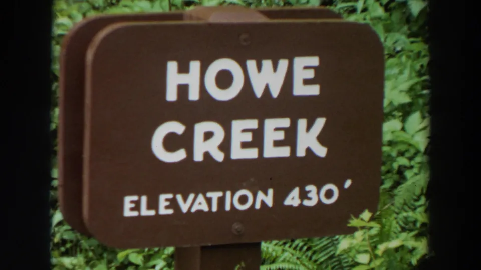 Final frame of the close-up on the Howe Creek Elevation 430 sign, seen against lush green foliage.