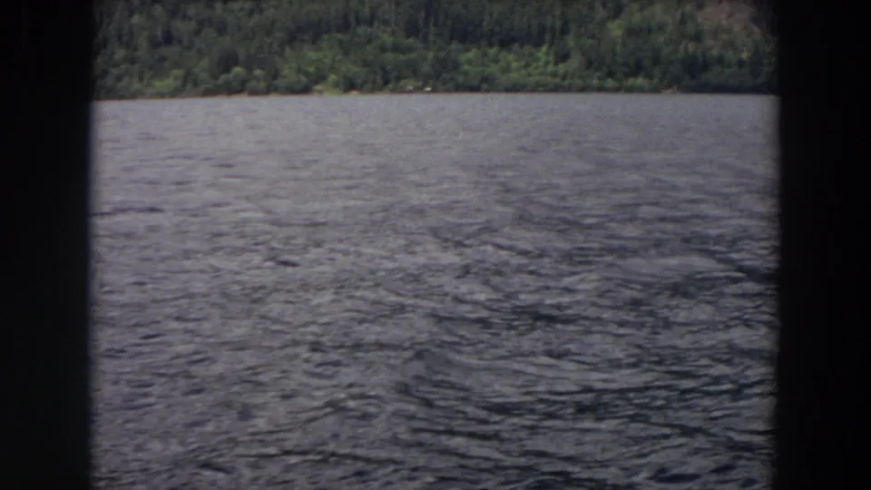 1964 Washington lake view with textured water, distant tree line, and dark vertical borders from the filmed framing.
