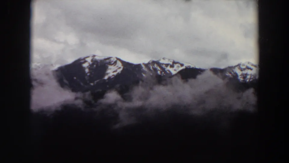 1964 Washington 8mm frame of a snowy mountain range and cloud cover, bordered by dark scan edges.