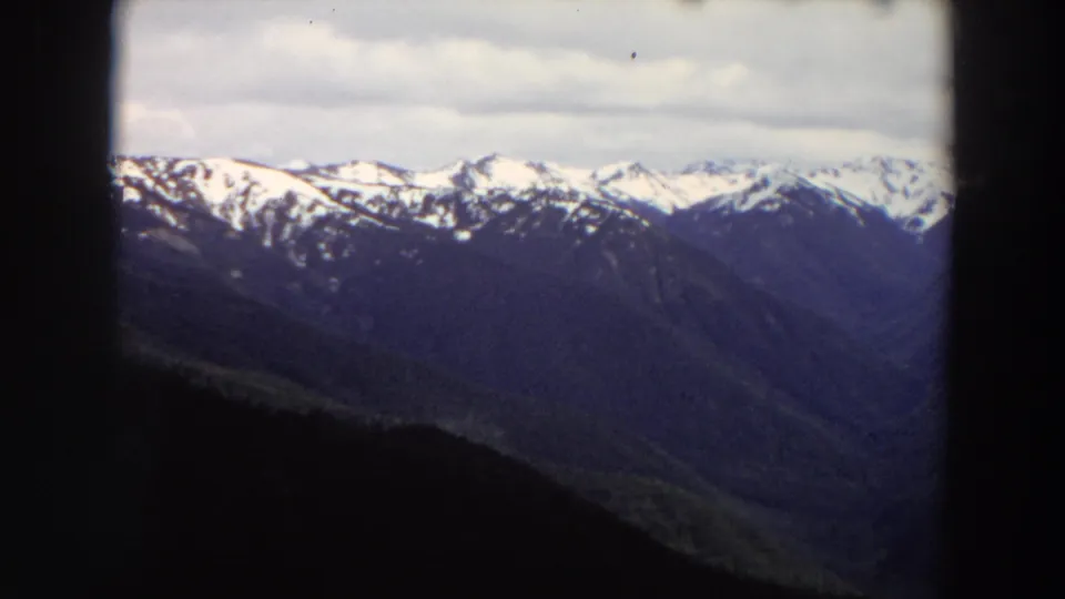 1964 Washington landscape view with layered mountain ridges and snow-bright peaks seen through a dark frame.