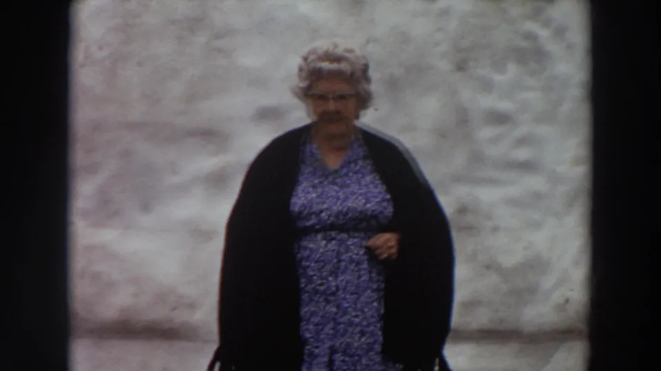 Older woman, likely a family member, stands outdoors in Washington in a patterned dress and dark wrap.