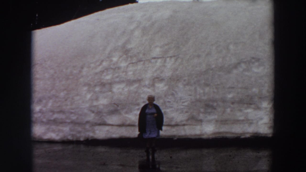 Woman standing before a tall snowbank or glacier-like wall.