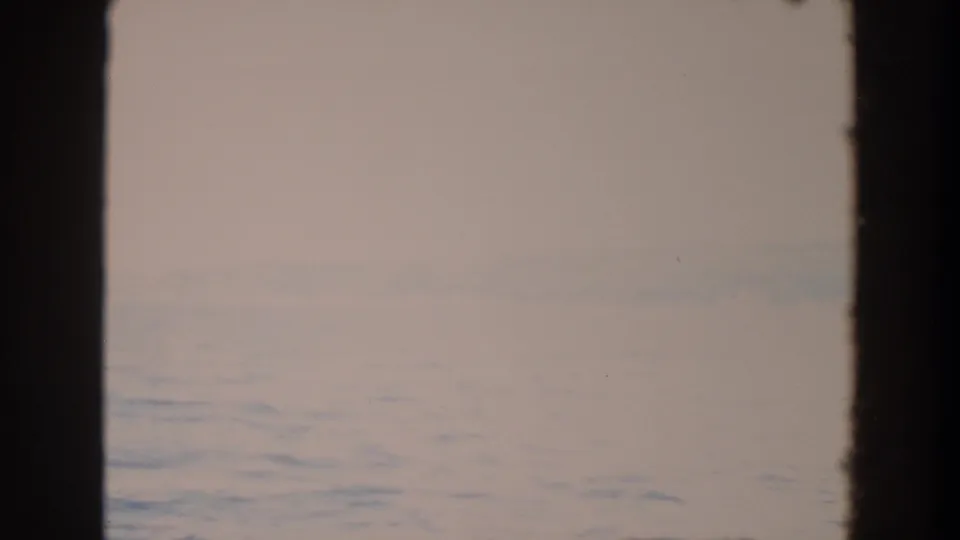 1964 Washington 8mm view of a pale misty ocean horizon with faint distant land and dark vertical edges in the frame.