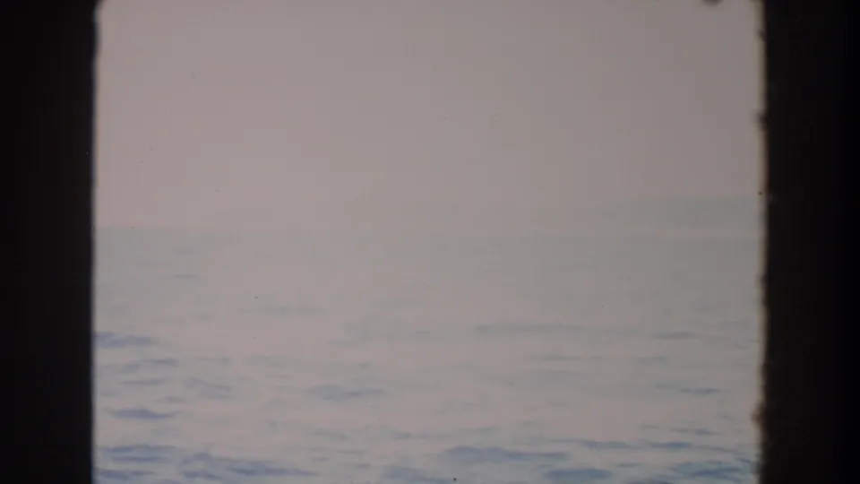 Faded 8mm footage shows calm coastal water under a pale sky, with the horizon softened by mist in Washington.